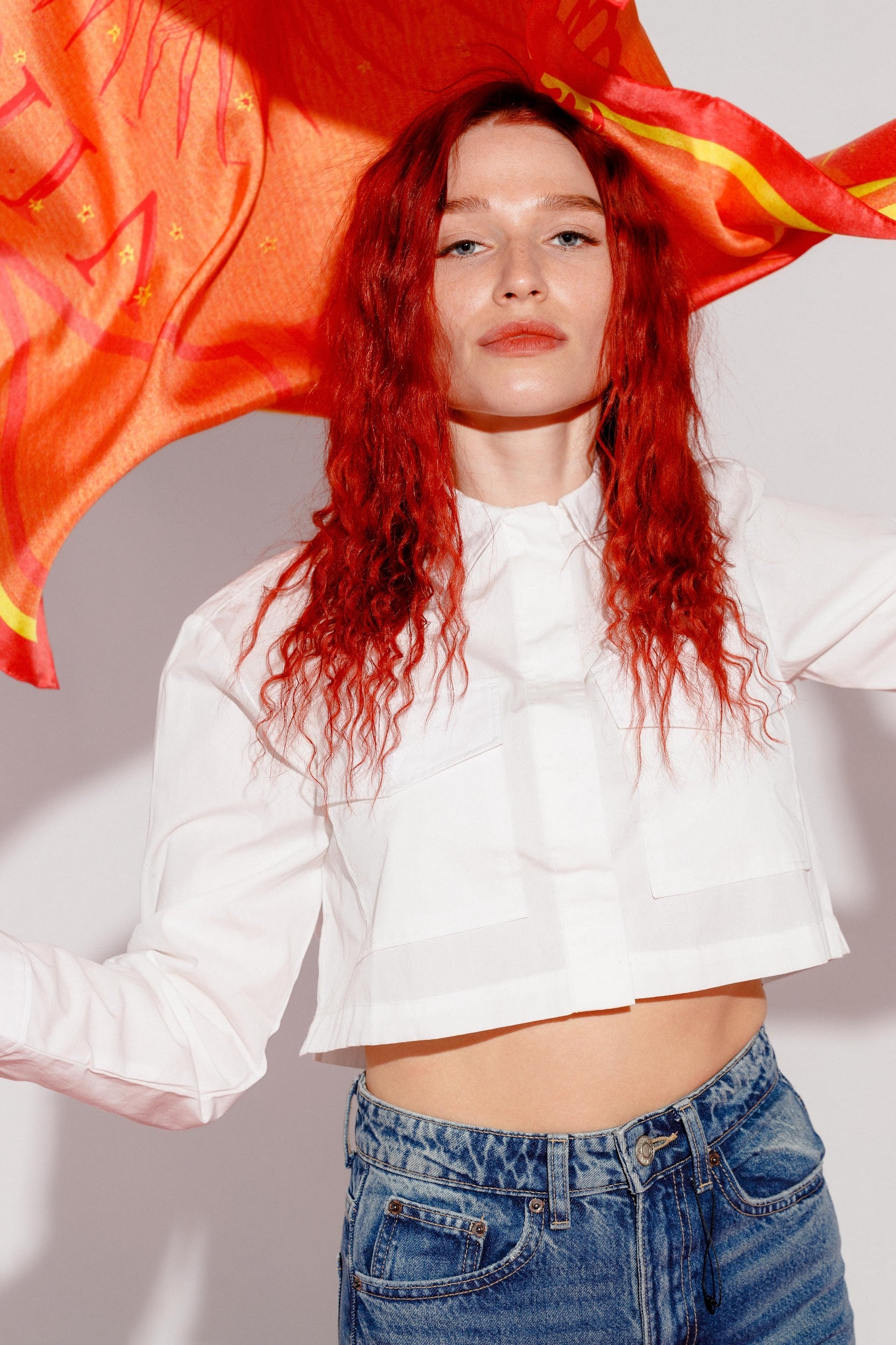 Model posing with pink silk twill square scarf flying over head