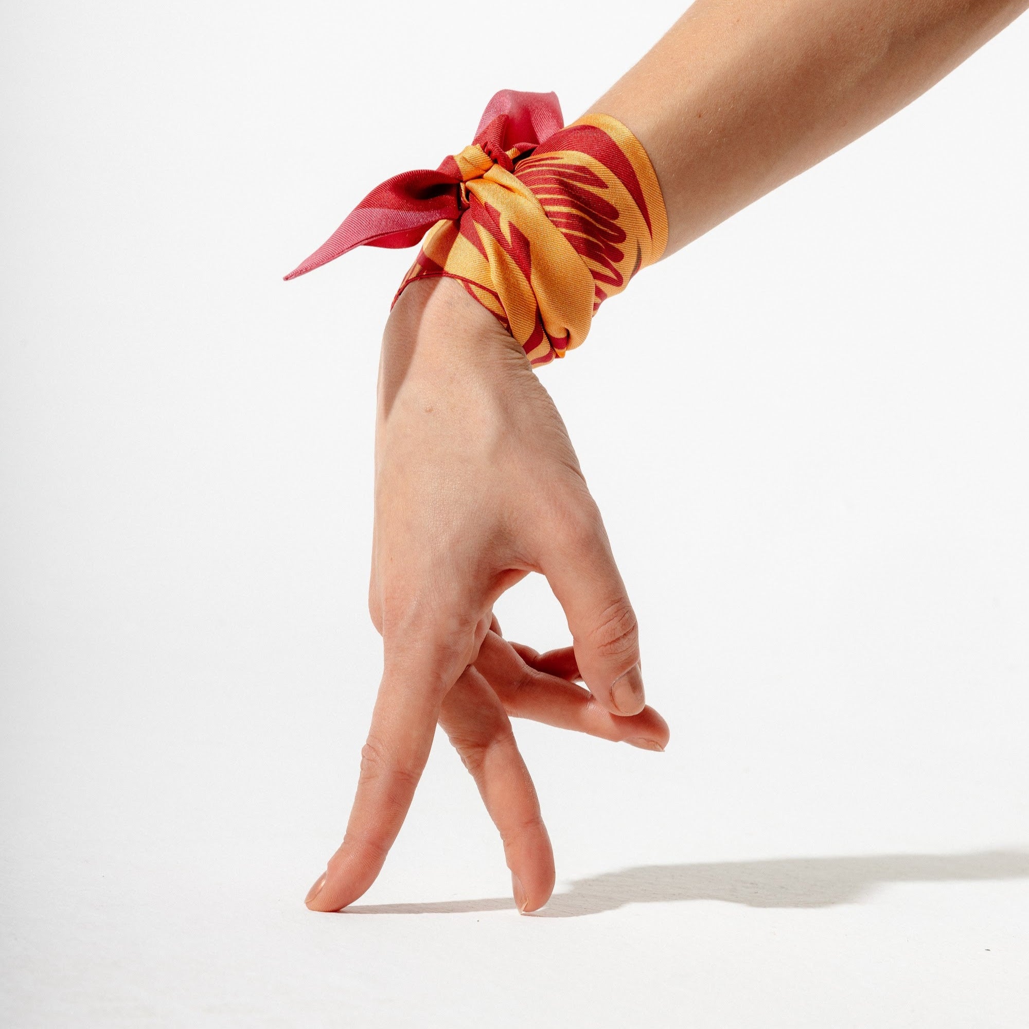 Silk twilly scarf in orange and pink tied around the hand
