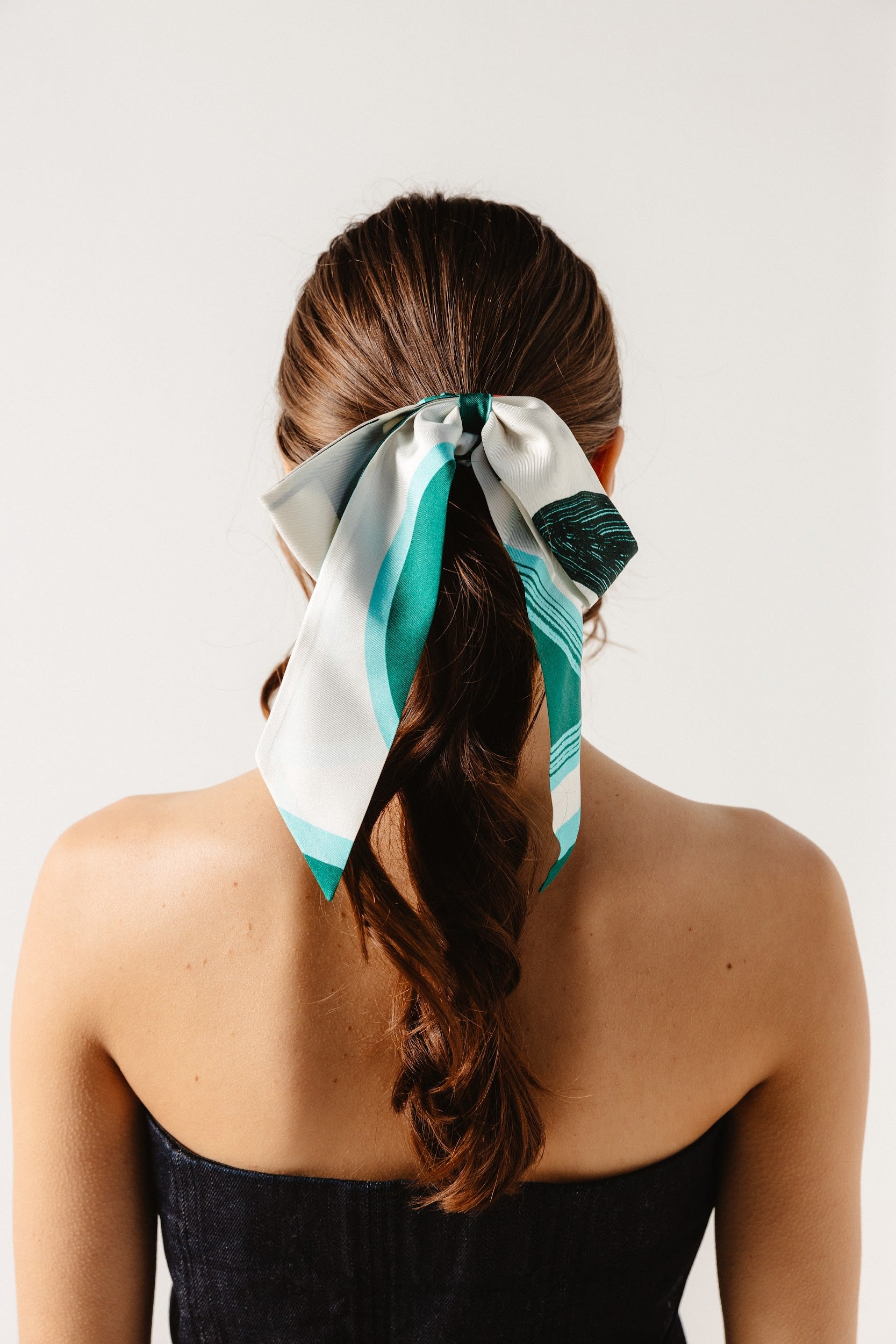 Model wearing silk scrunchie with bow around ponytail