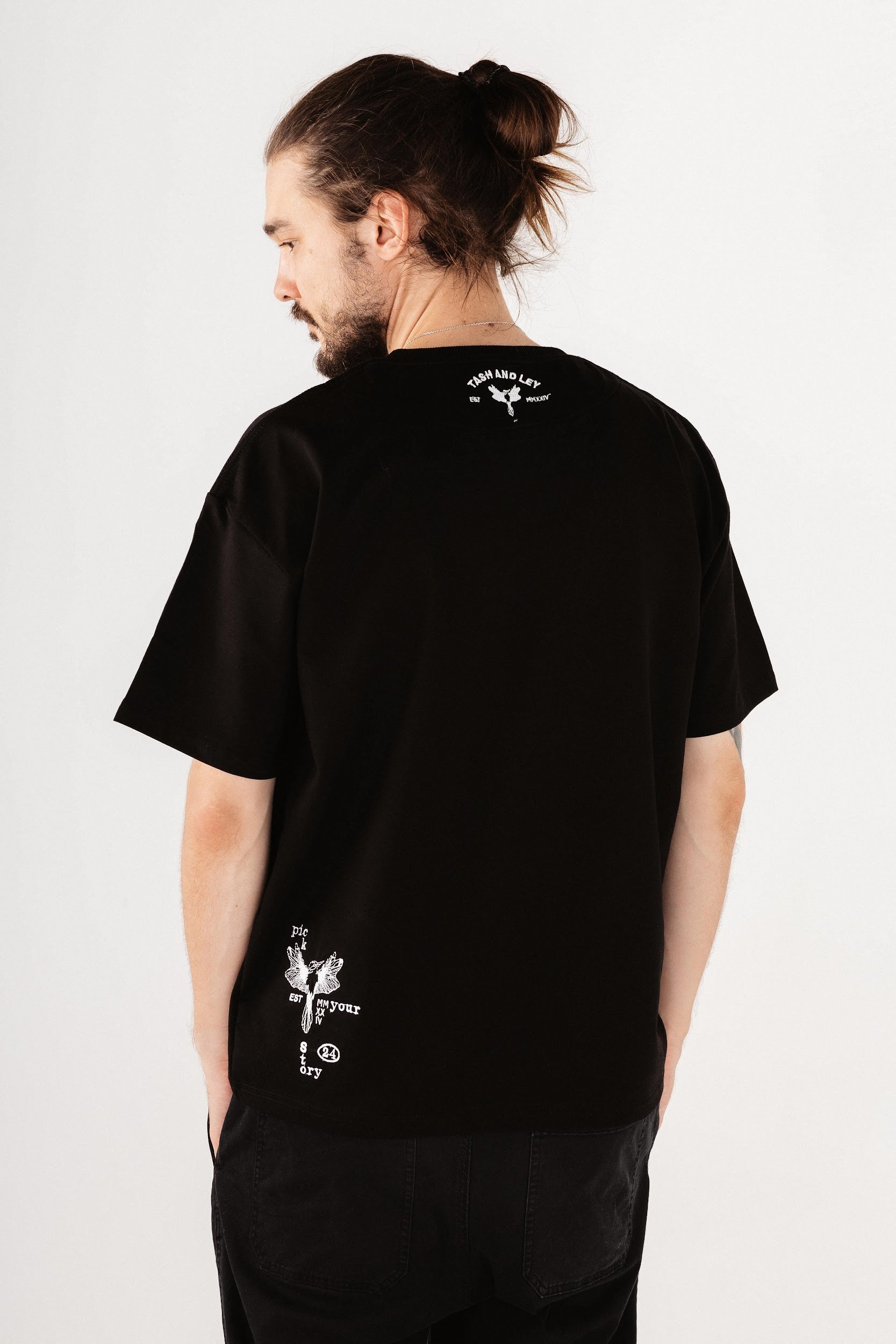 Male model wearing black top with hummingbird design embroidery on back