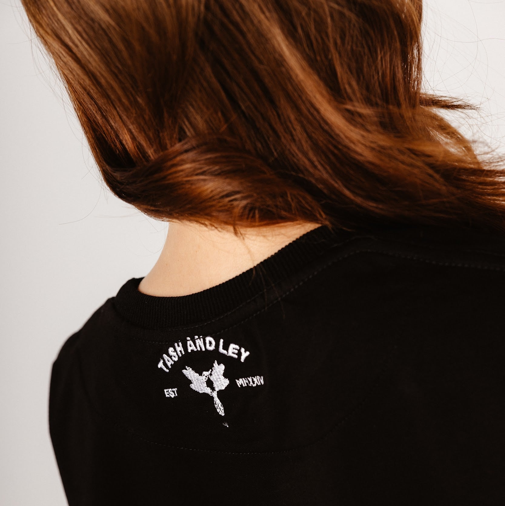 Details of black top with tash and ley logo embroidered in white on back