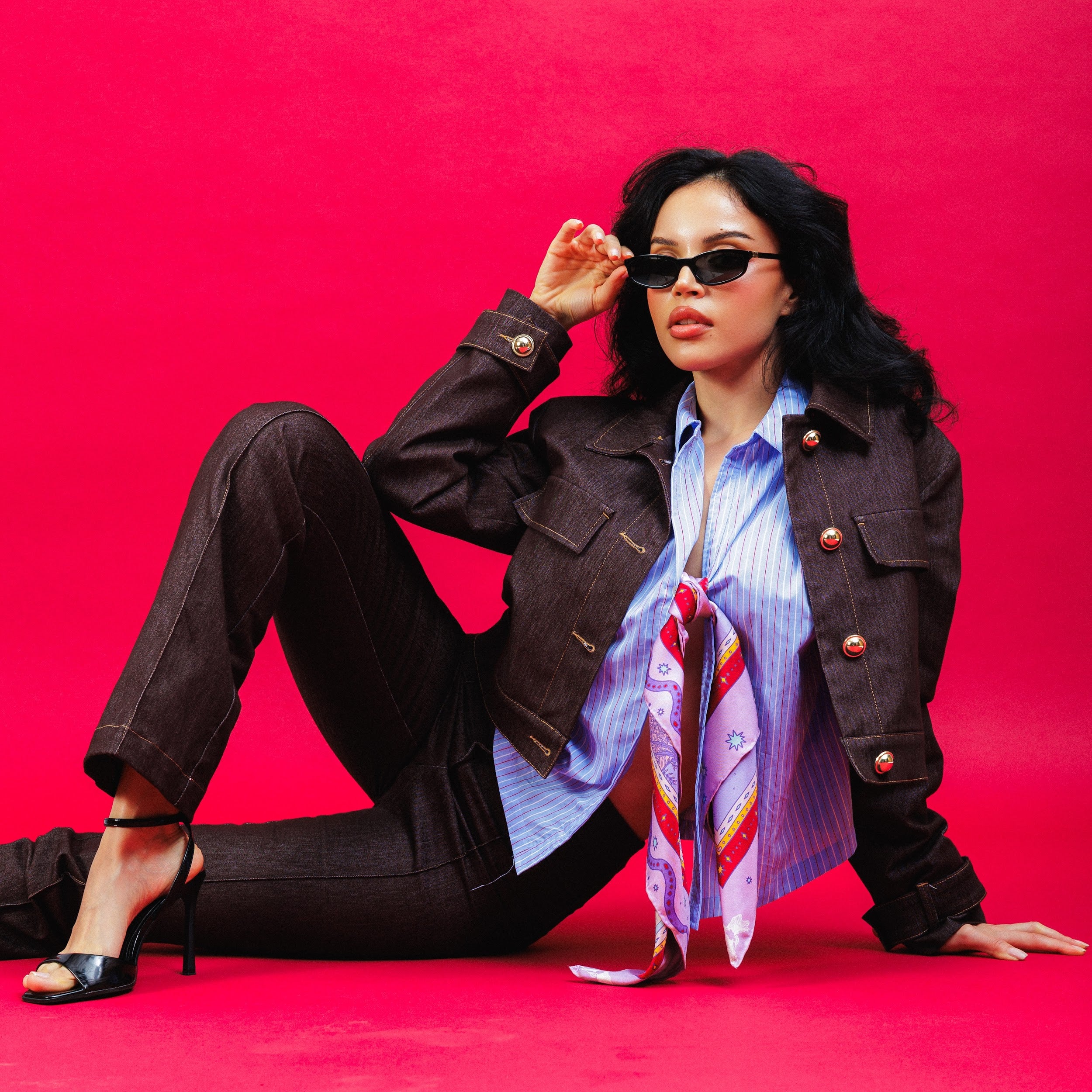 Model posing on a fuschia background with silk scarf styled on shirt