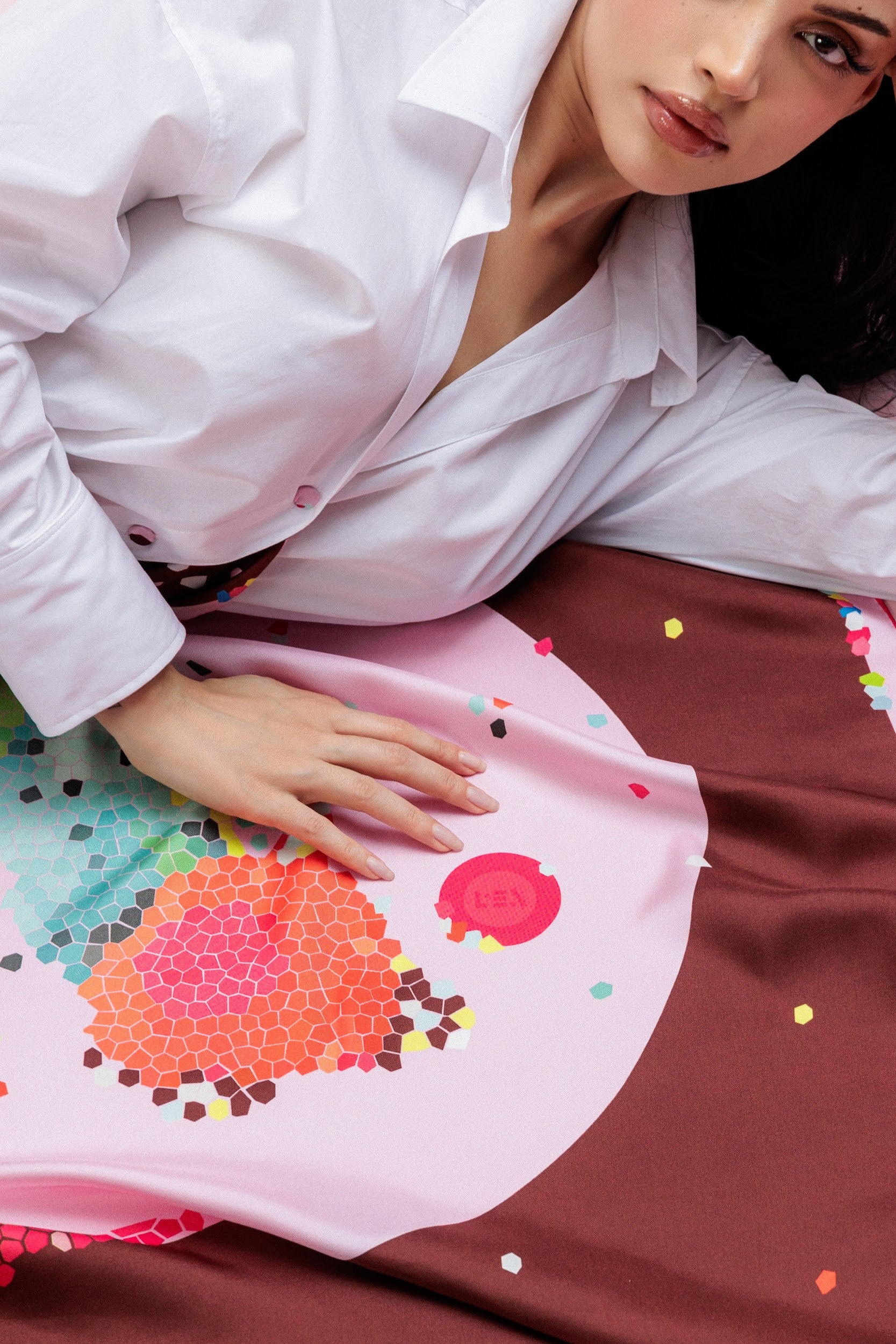 Model wearing a white shirt with a colorful scarf featuring abstract patterns