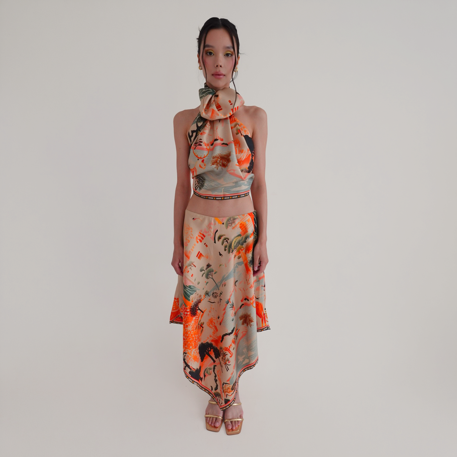 Woman wearing a colorful set with a silk scarf as a top and an asymmetrical skirt