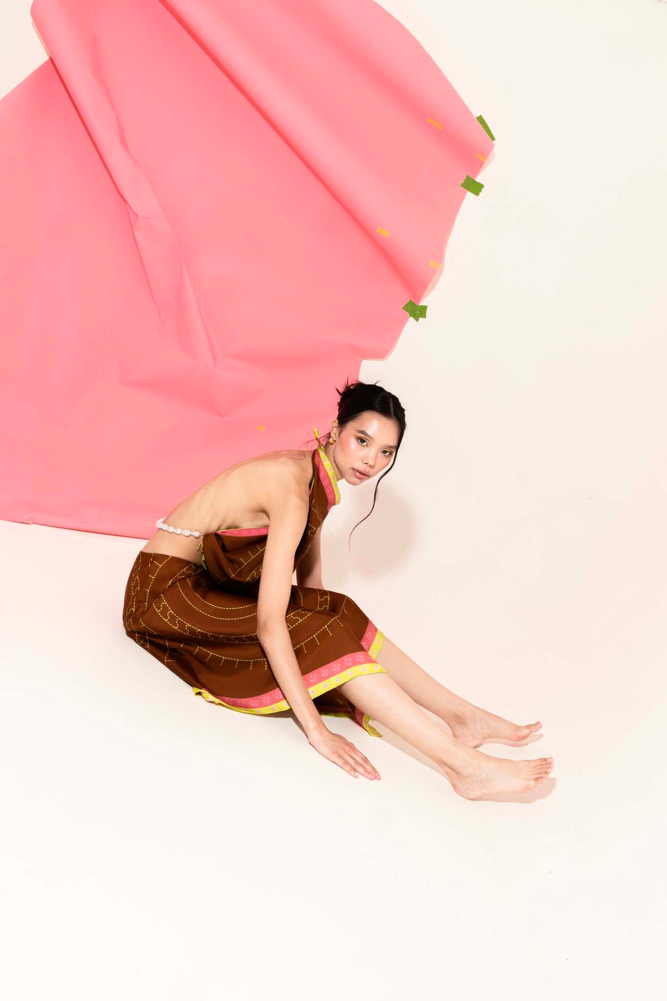Woman in brown set with a silk scarf as a top and asymmetrical skirt