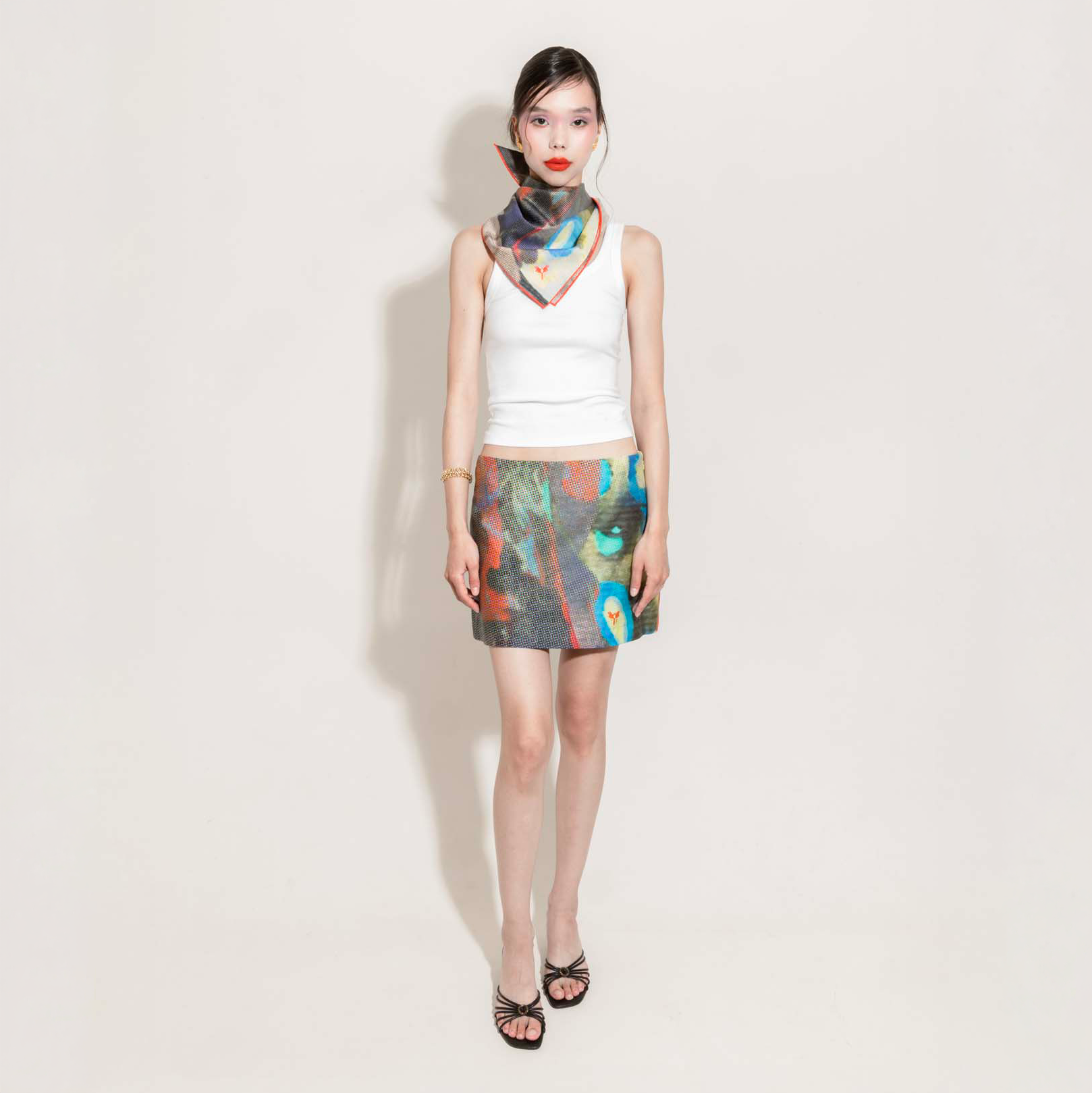 Woman wearing a white top and colorful skirt with matching scarf around the neck