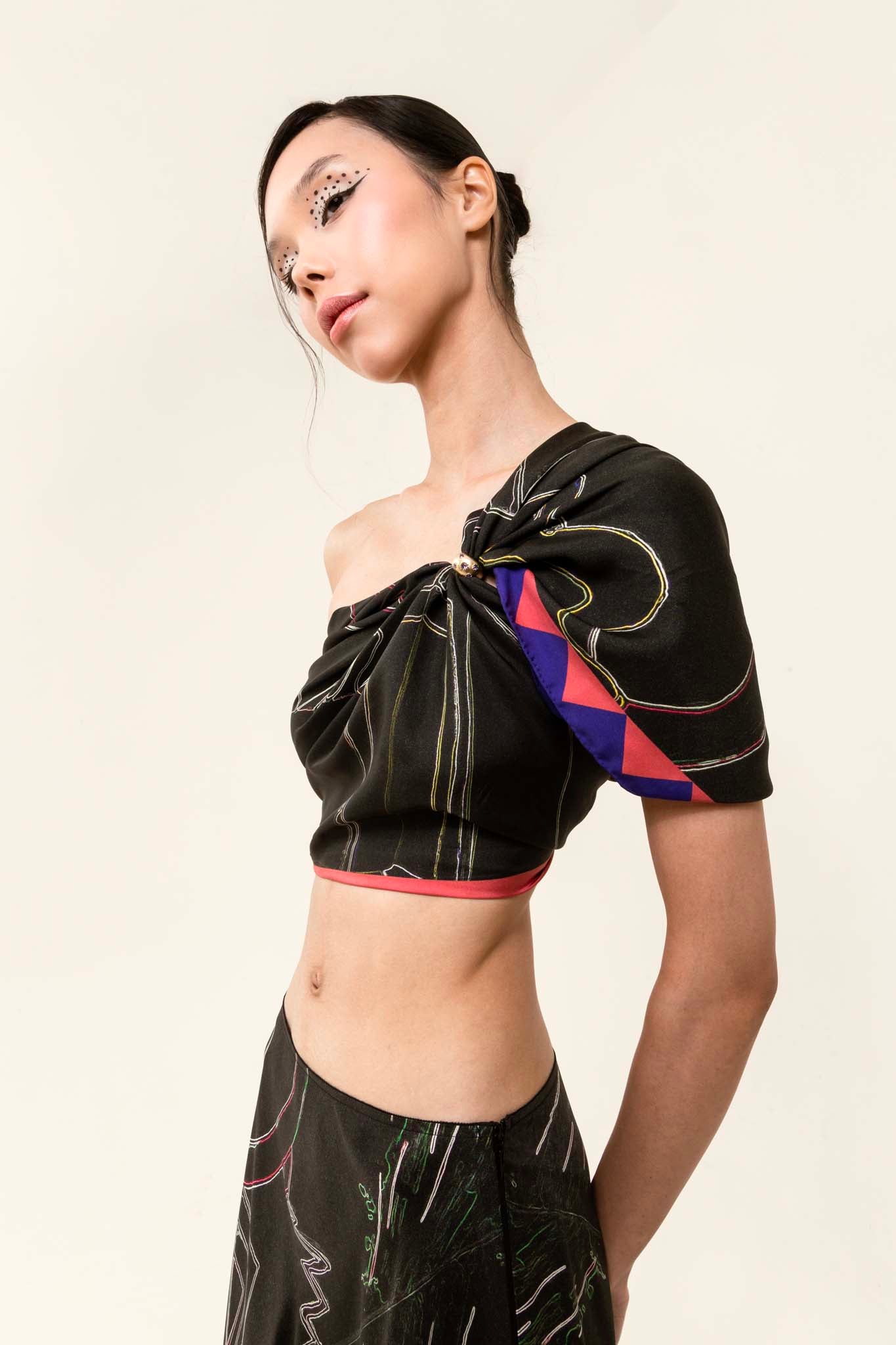 Model wearing a black set with a silk scarf as a top and matching skirt
