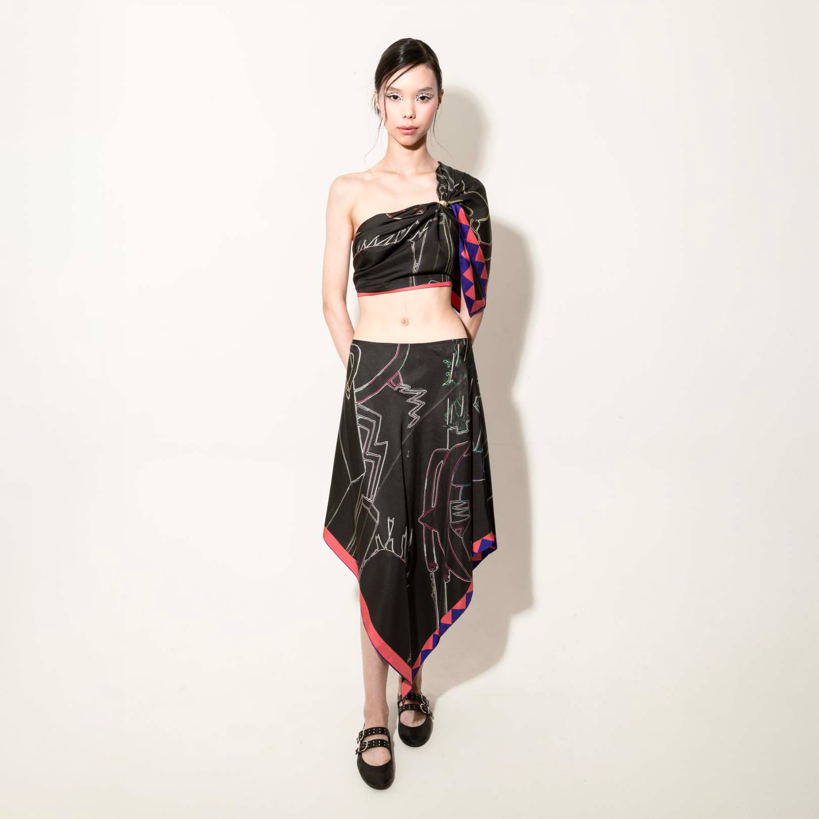 Model wearing a black set with a silk scarf as a top and asymmetrical skirt