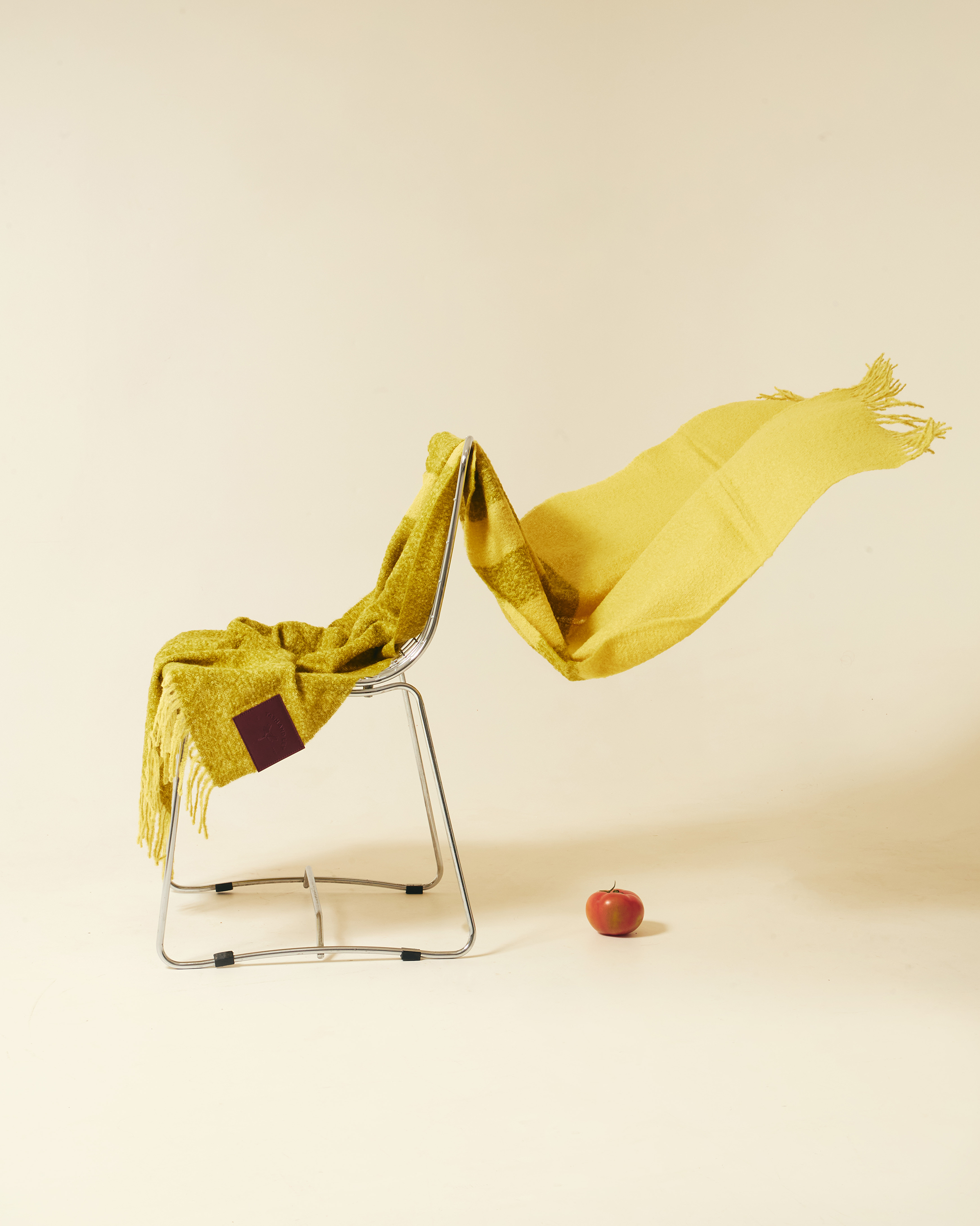 Yellow and green alpaca wool scarf draped over a chair on white background