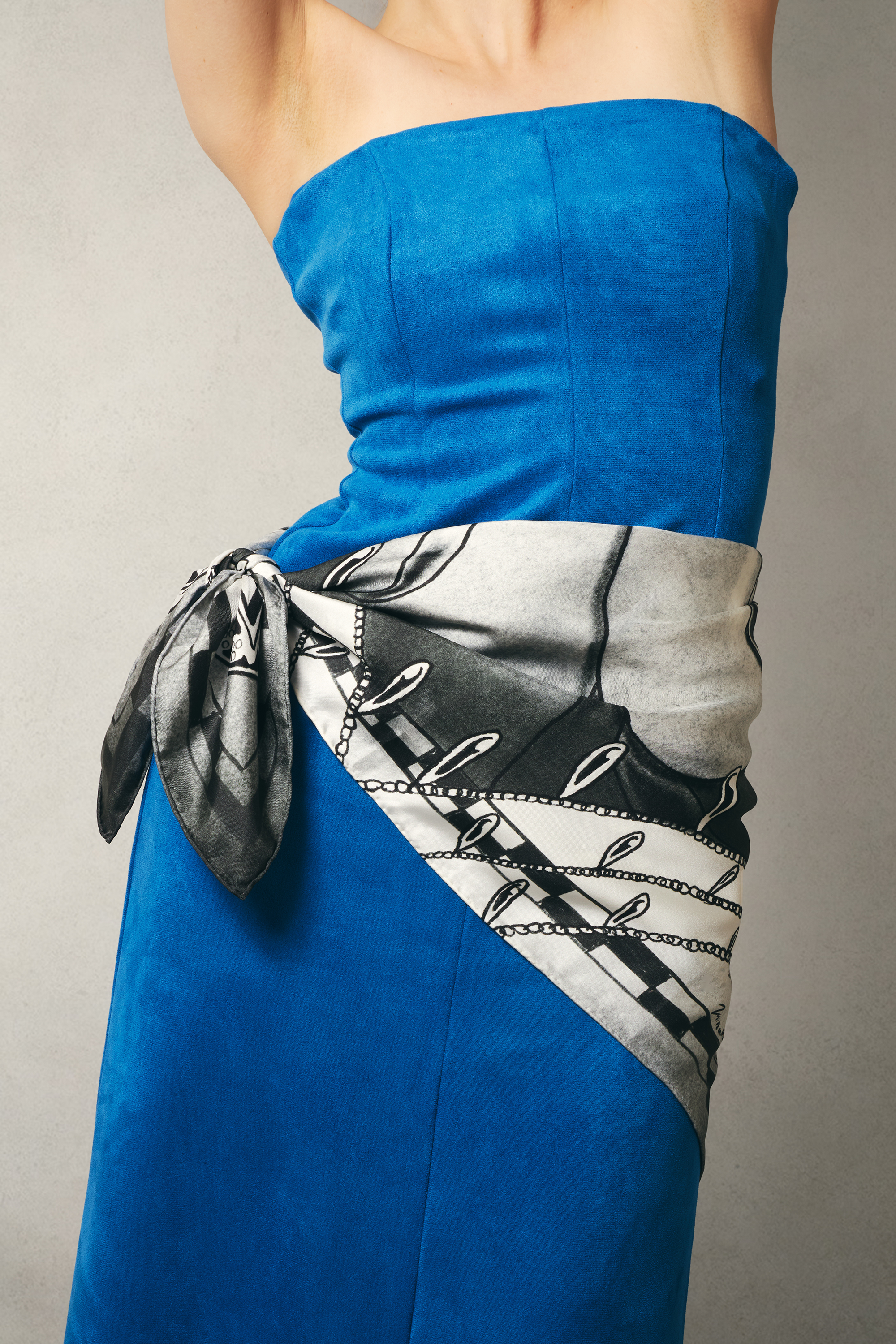 Woman wearing blue strapless dress with a black and white patterned scarf draped over waist