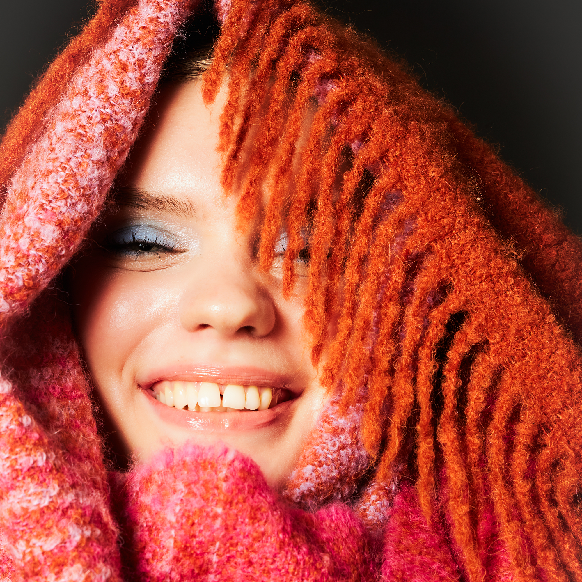 Person close up on face wrapped in a pink and orange alpaca wool scarf