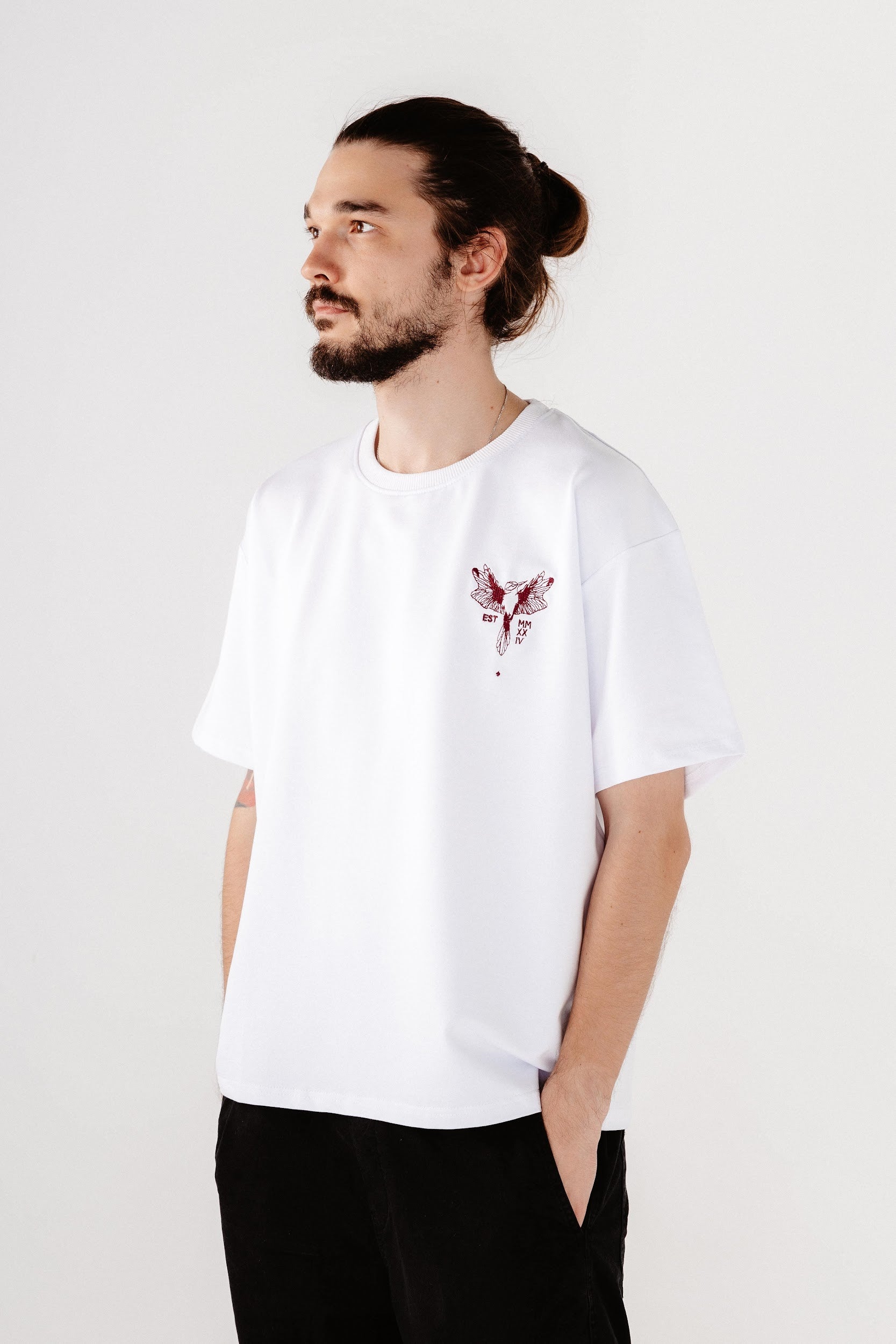 Male model wearing white oversized  top with dark red bird embroidered in front