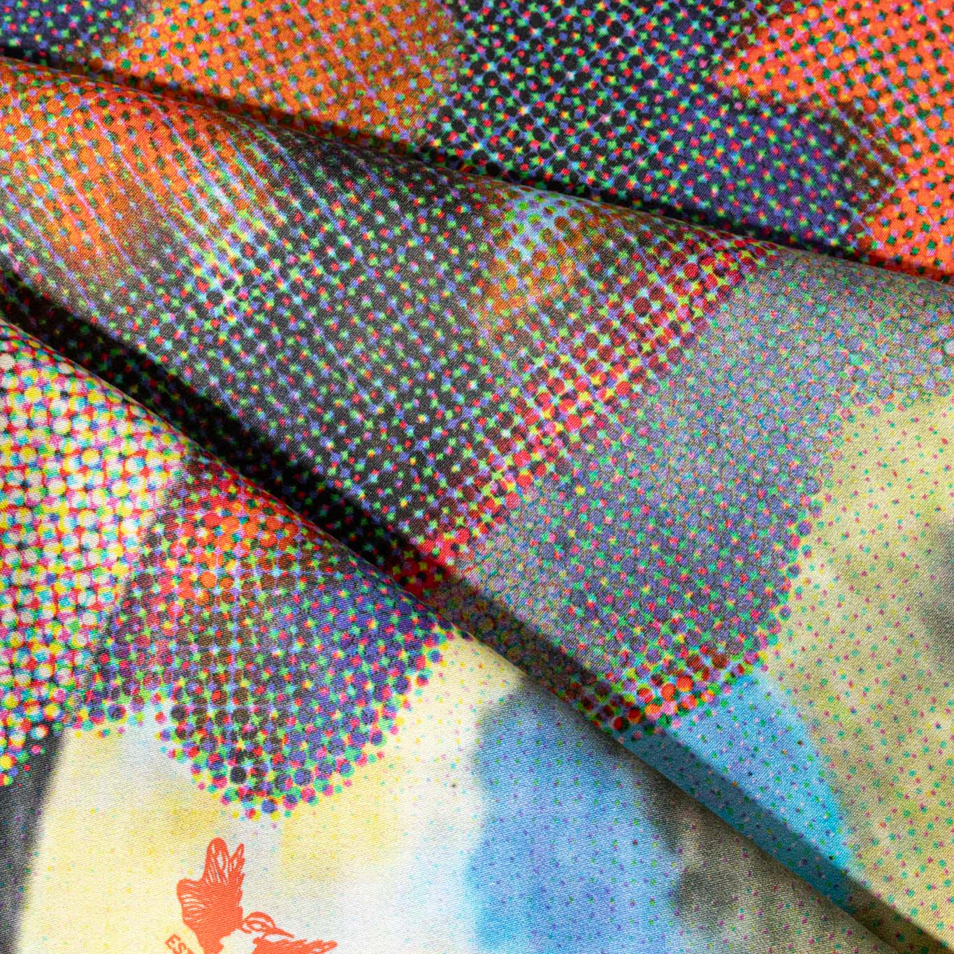 Close-up of a colorful cotton scarf with abstract patterns and a small red bird design.