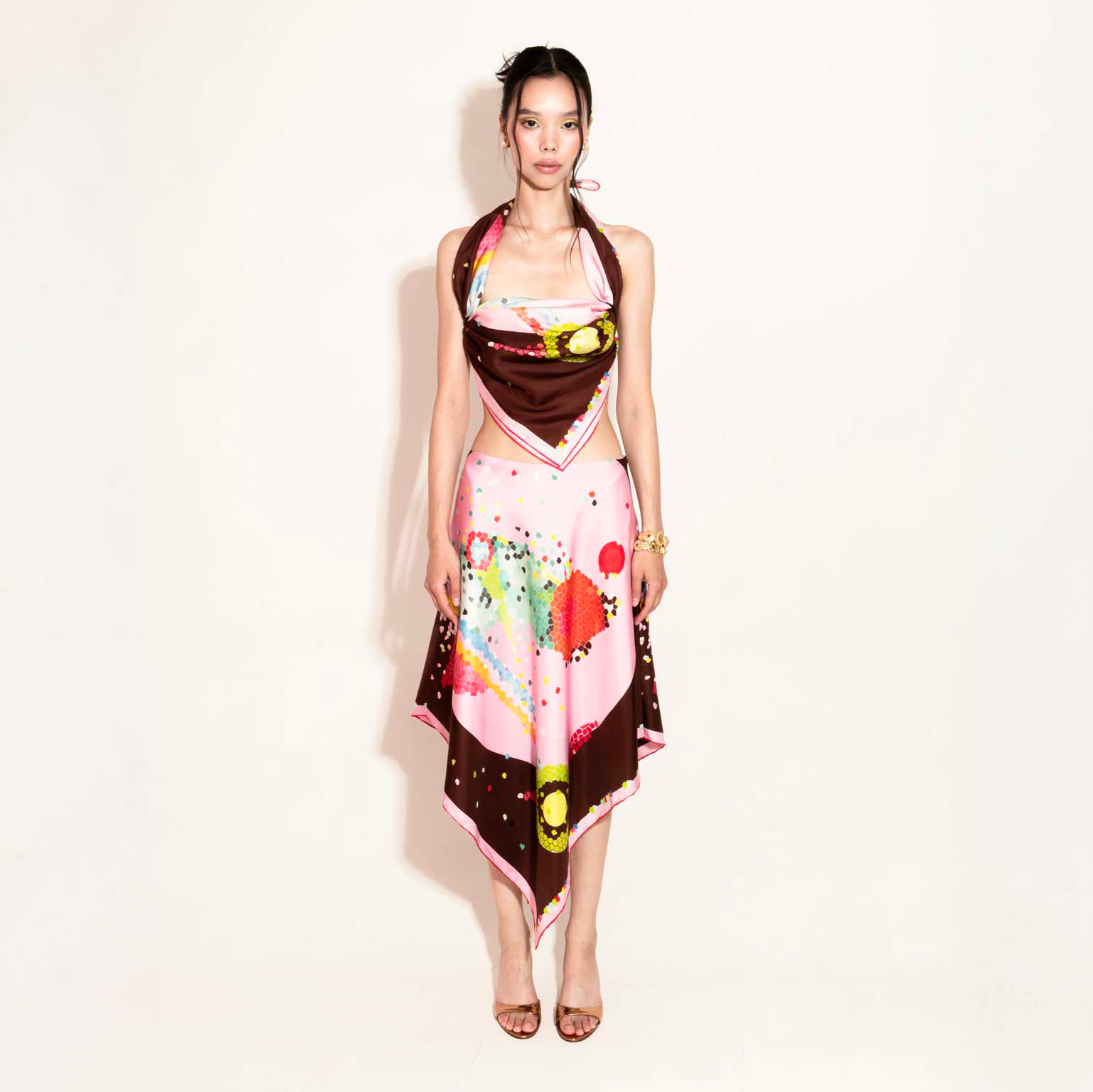 Model wearing a colorful set with a silk scarf as a top and asymmetrical skirt