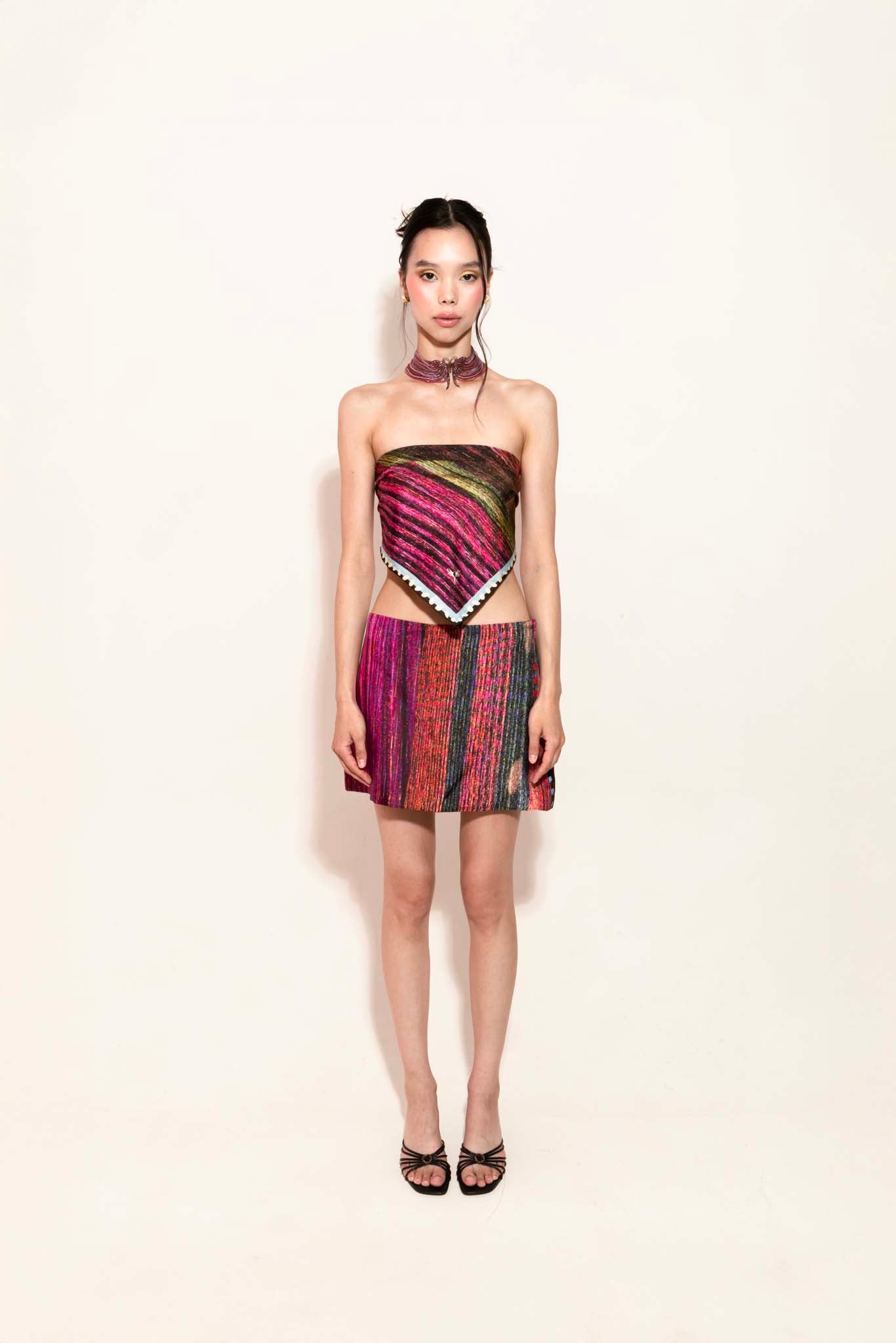 Model wearing a colorful set with a square silk scarf as a top and a matching silk skirt 