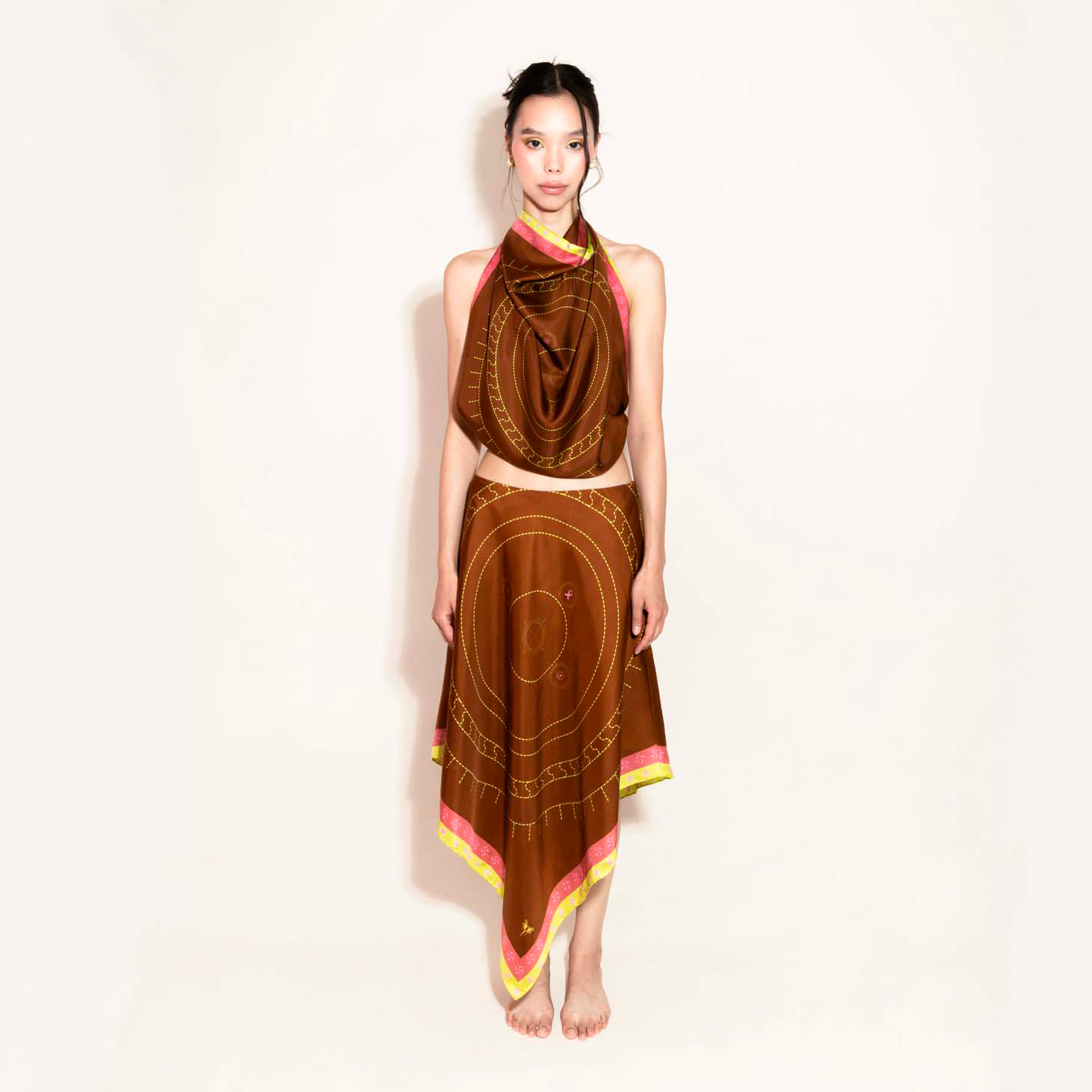 Model wearing a set with a brown geometric design with a scarf as a top and asymmetrical skirt