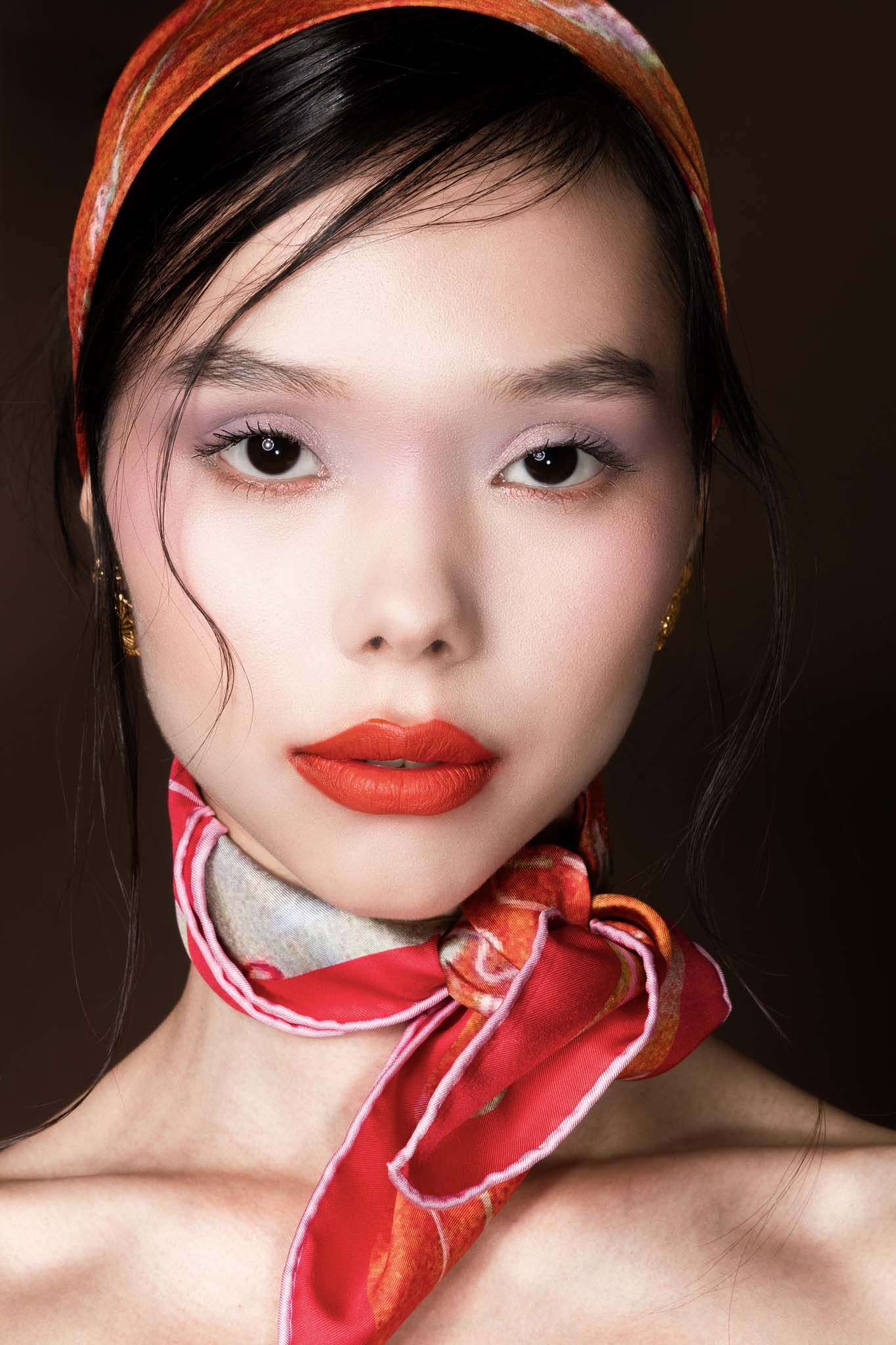 Close-up of woman wearing an orange and red silk scarf on her head