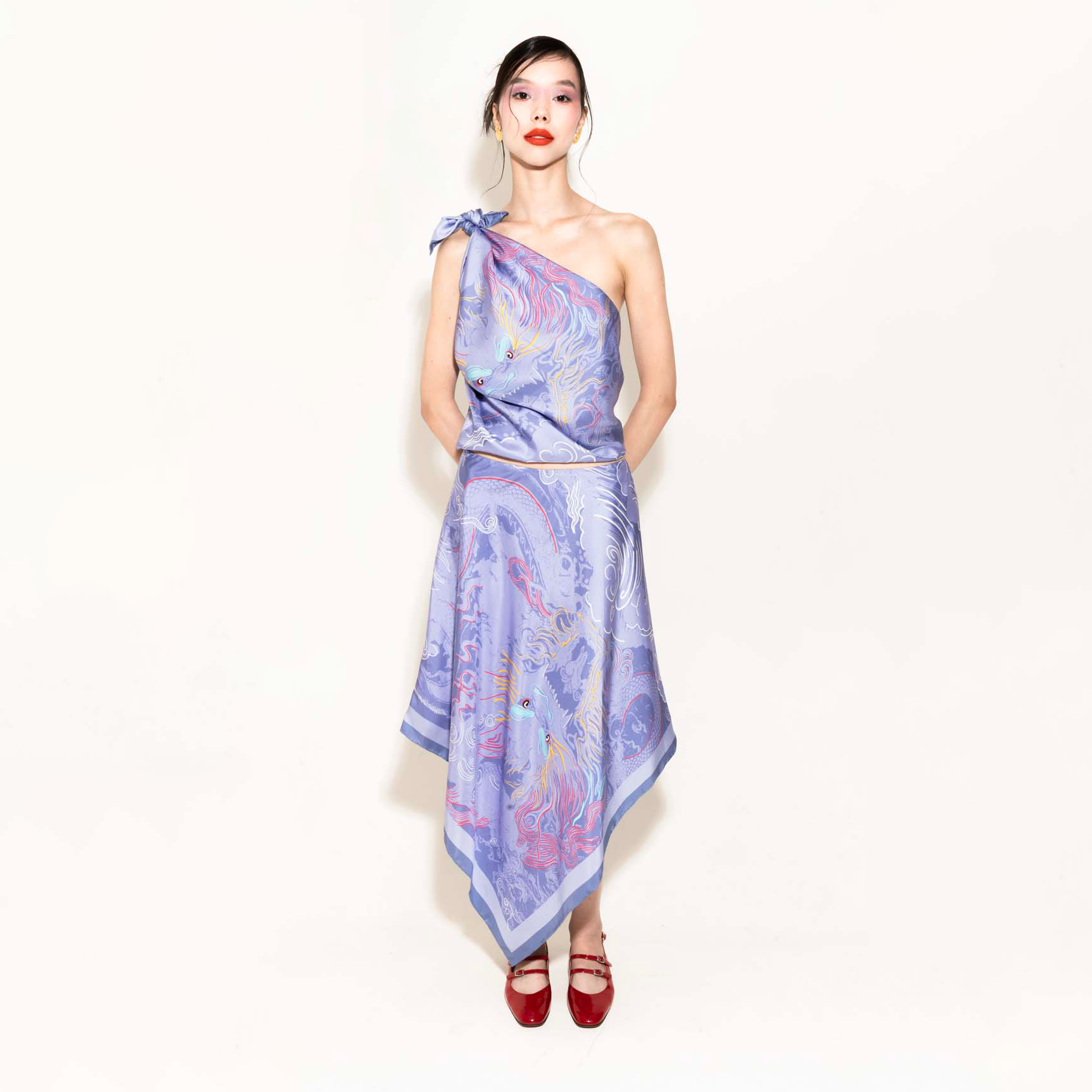 Woman wearing a purple dragon design matching set with a silk scarf as a top and an asymmetrical skirt