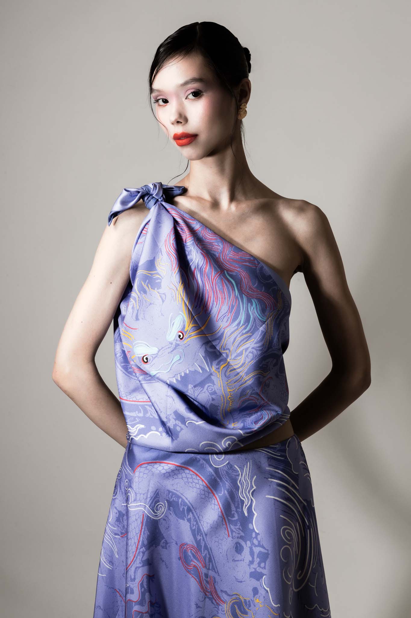 Woman wearing a purple dragon design matching set with a silk scarf as a top and an asymmetrical skirt