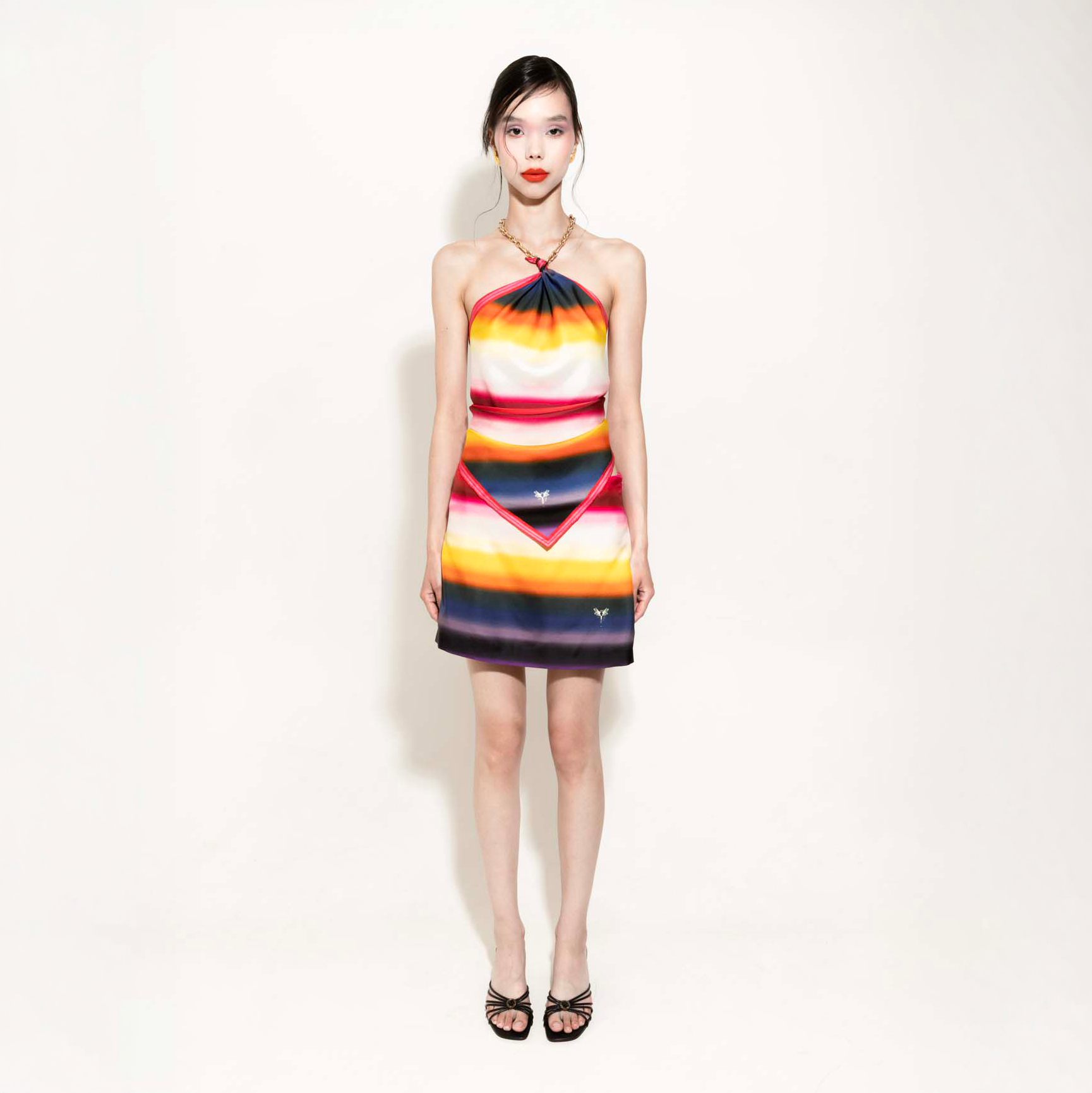 Woman wearing a colorful striped rainbow set with a silk scarf as a top and a skirt