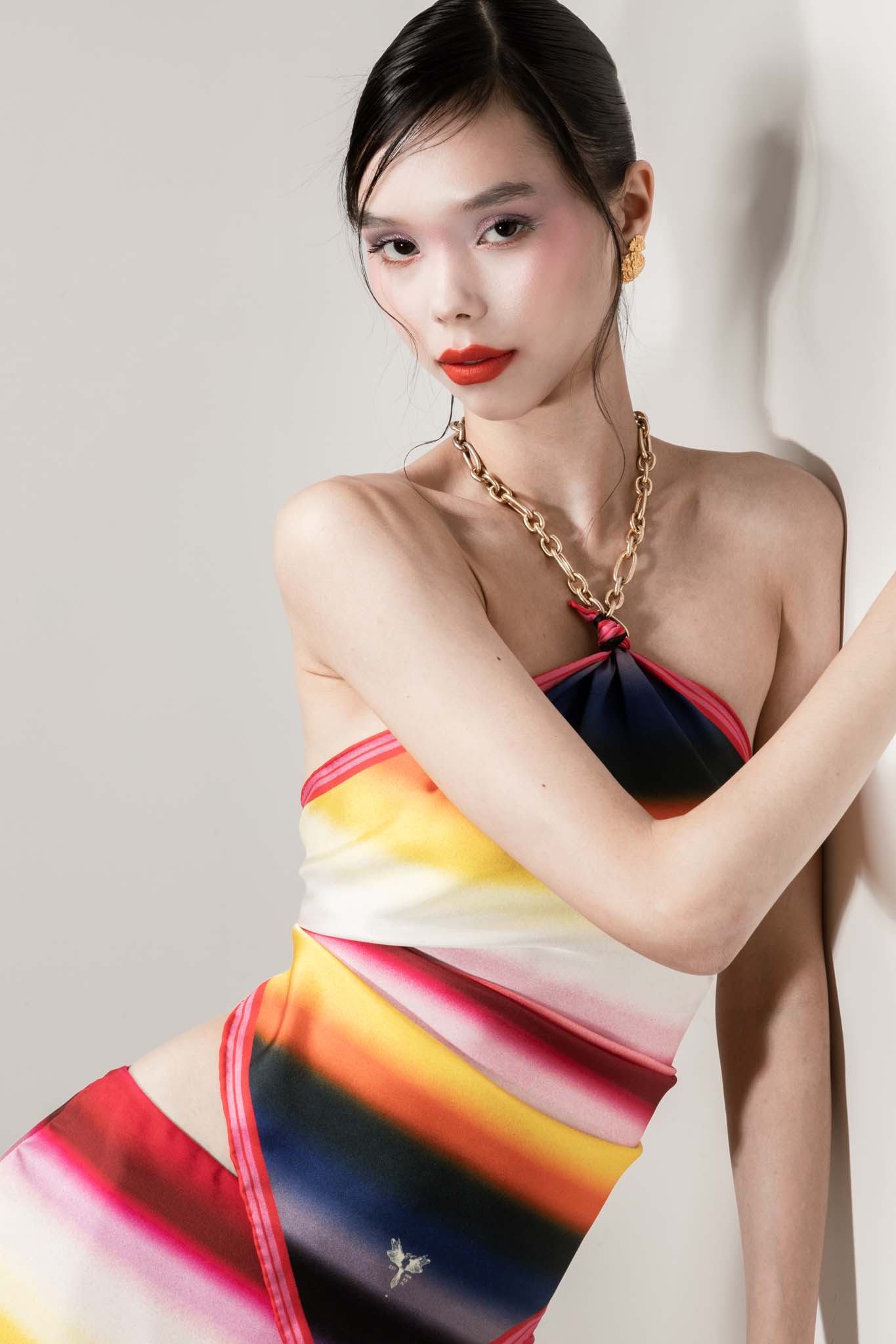 Woman wearing a colorful square silk scarf as a top with a chain necklace