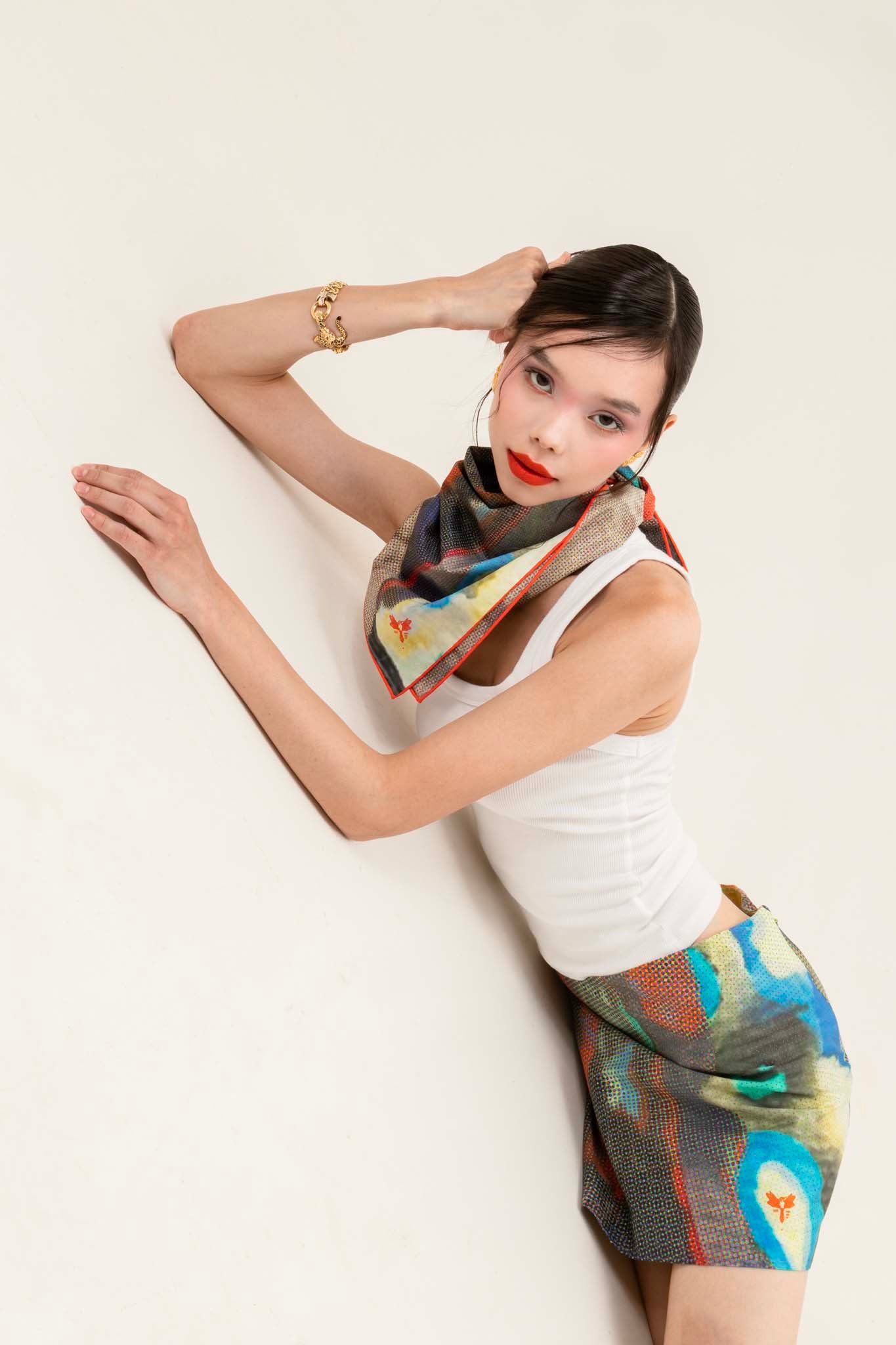 Woman wearing a colorful scarf and matching skirt against a white background