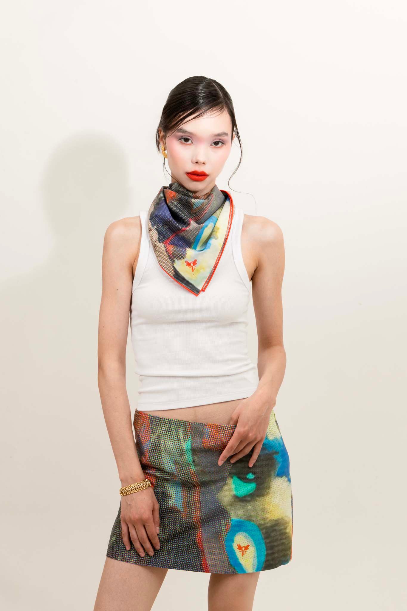 Woman wearing a colorful scarf and matching skirt with a white background