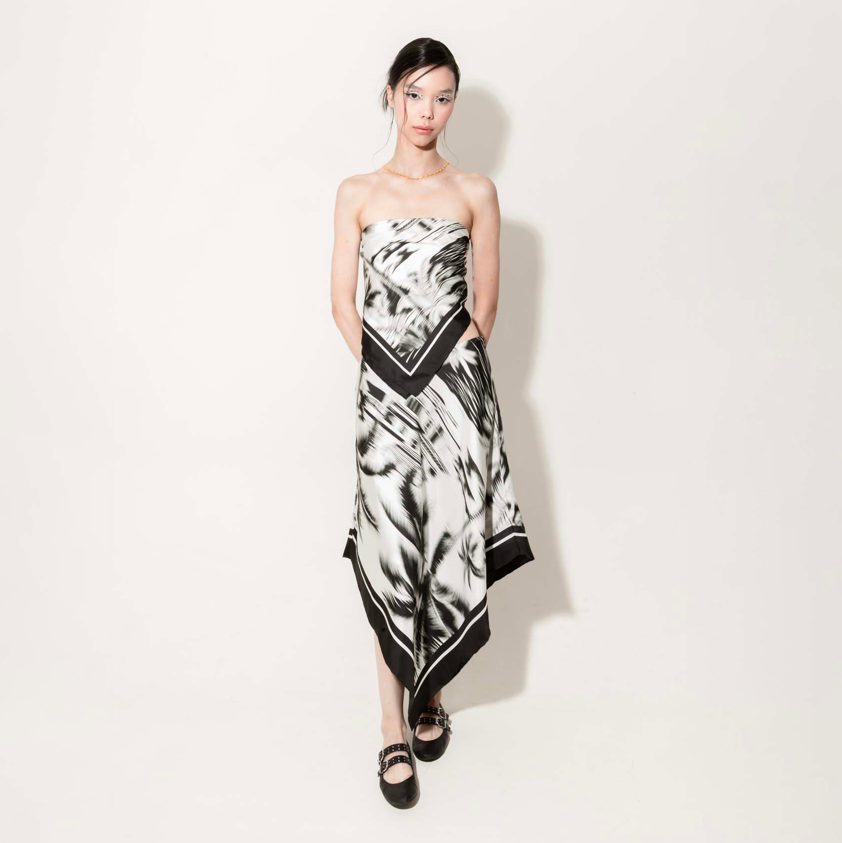 Woman wearing a black and white set with a silk scarf as a top and asymmetrical skirt