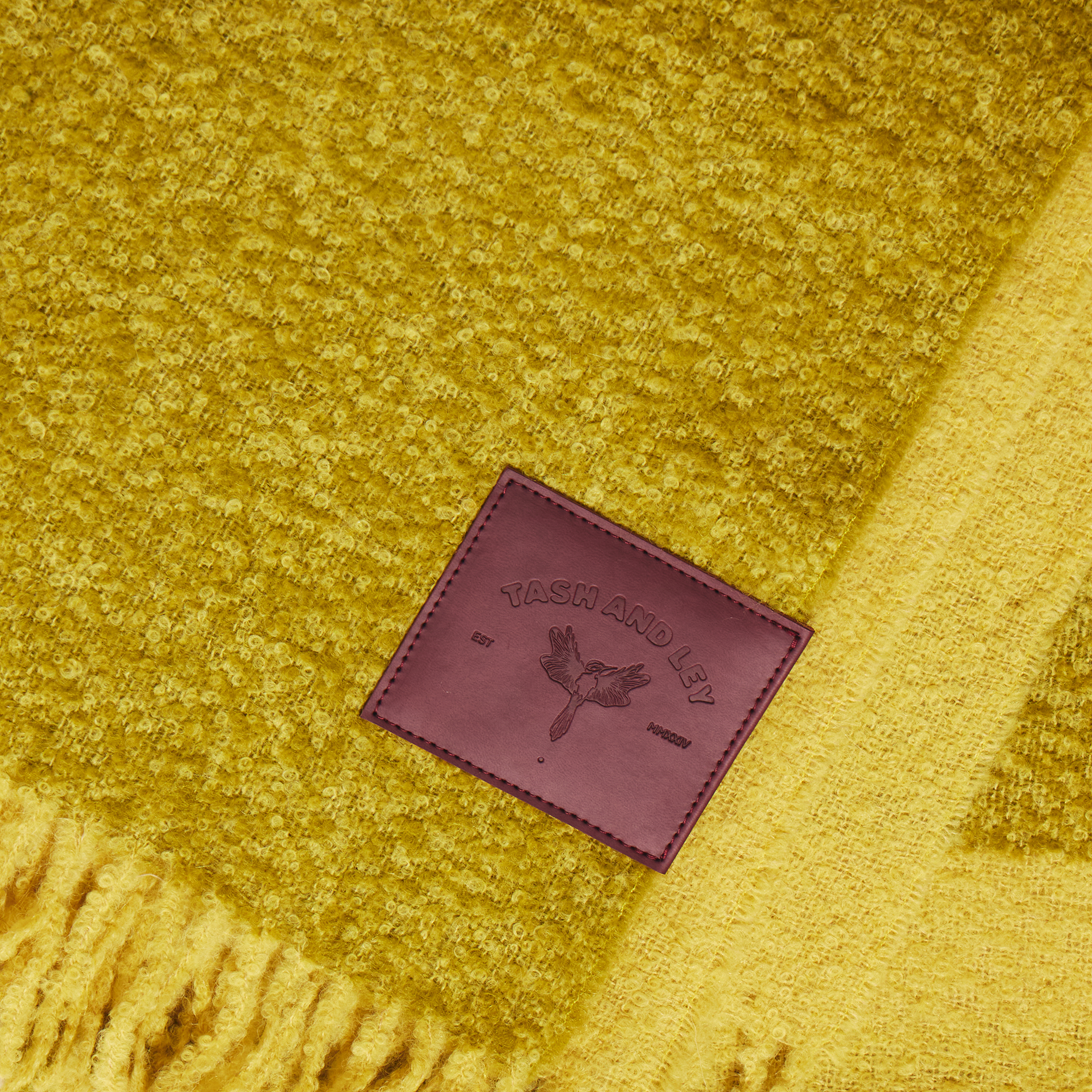 Yellow and green alpaca wool scarf with a burgundy label featuring TASH AND LEY logo