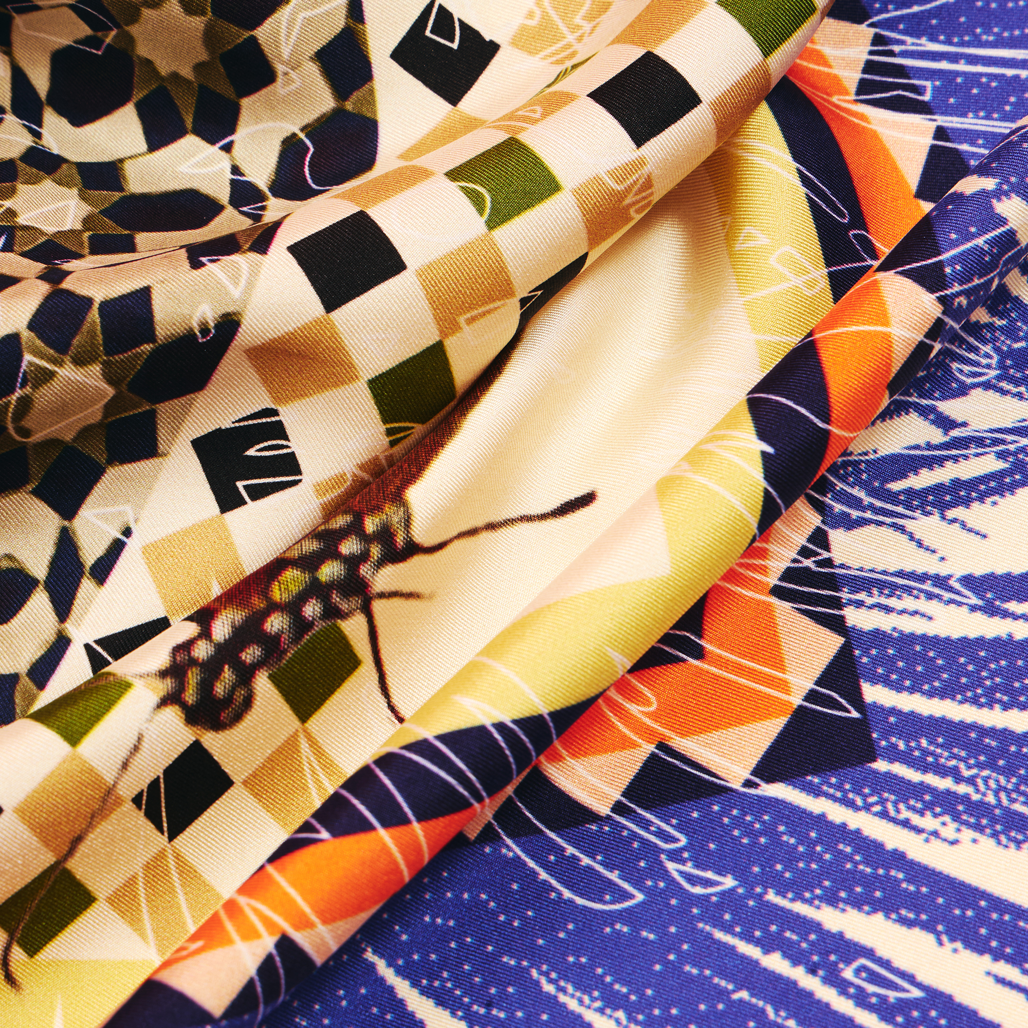 Close-up details of silk twill scarf with beige and blue design with various patterns