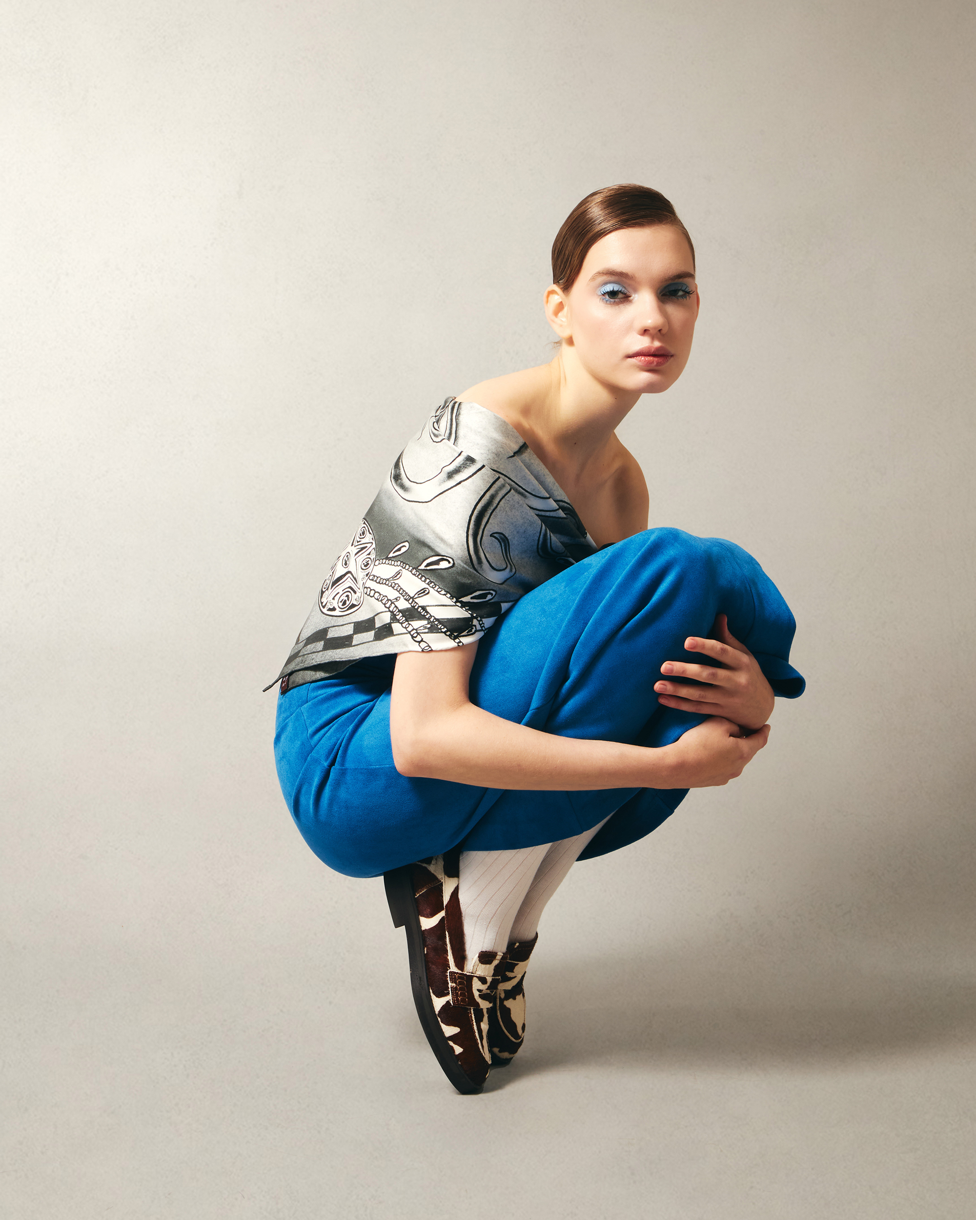 Woman wearing a blue outfit with a gray black and white silk scarf around shoulders
