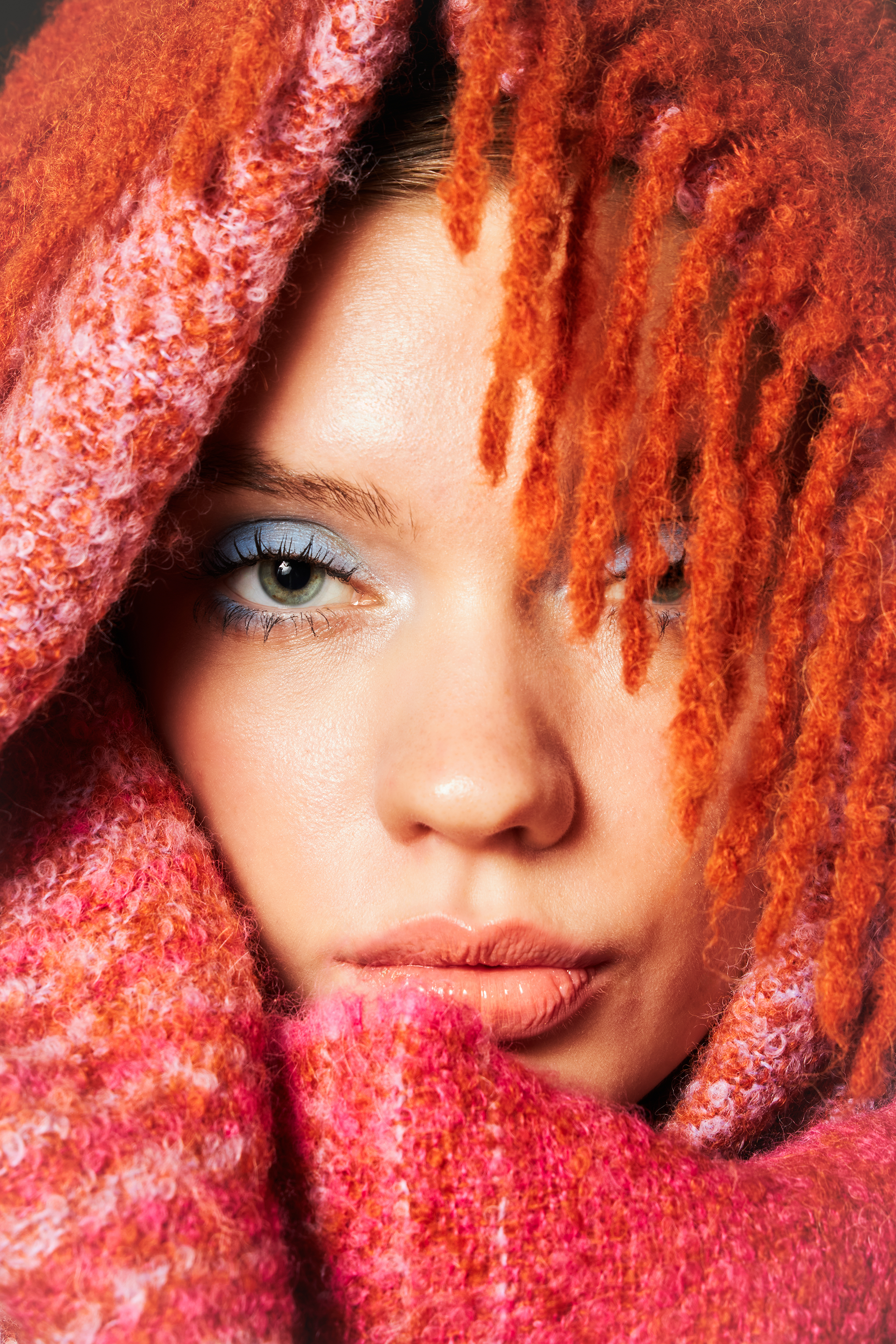 Close up on face wrapped in a pink and orange alpaca wool scarf