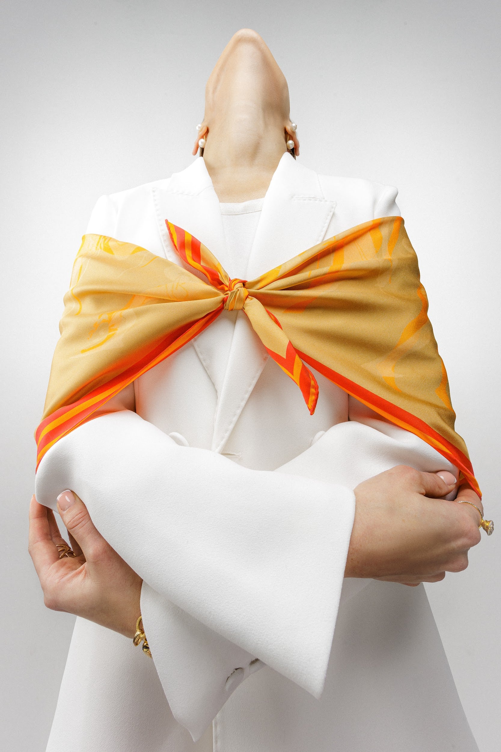 Model wearing silk twill square scarf with orange print around shoulders